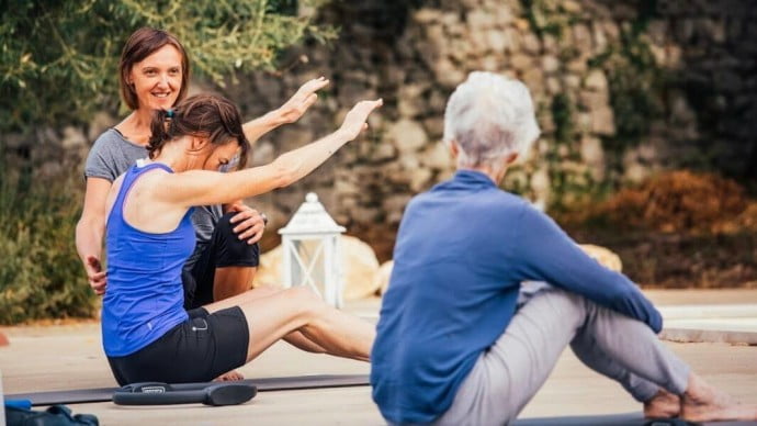 3 ladies doing a Pilates lesson outdoors on their solo travel holiday