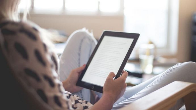 A woman listening to an audio book off of her tablet