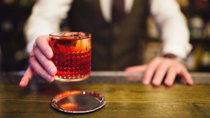 A bar tender serving a Negroni cocktail in an Italian bar