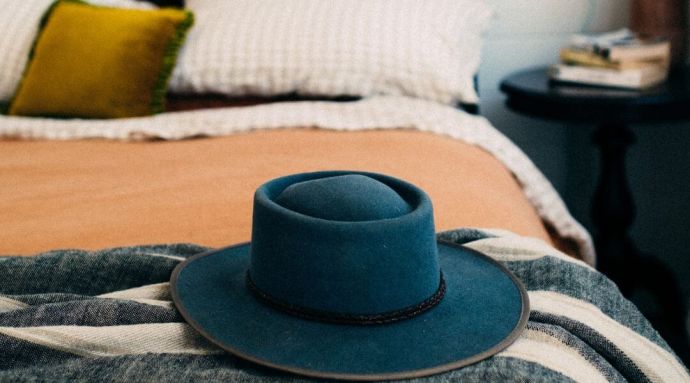 A blue hat placed on the edge of a bed