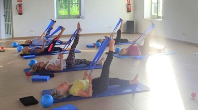 Ladies stretching their legs with a Pilates band 