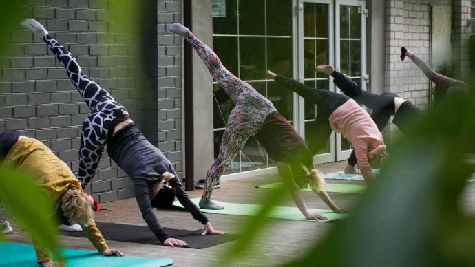 Our favourite wellness podcasts for this year - Pilates class in one legged downward dog position