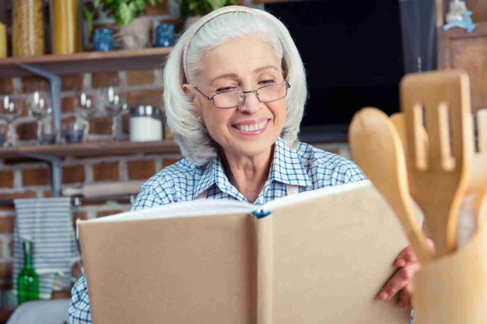 Lady reading a cook book in the kitchen
