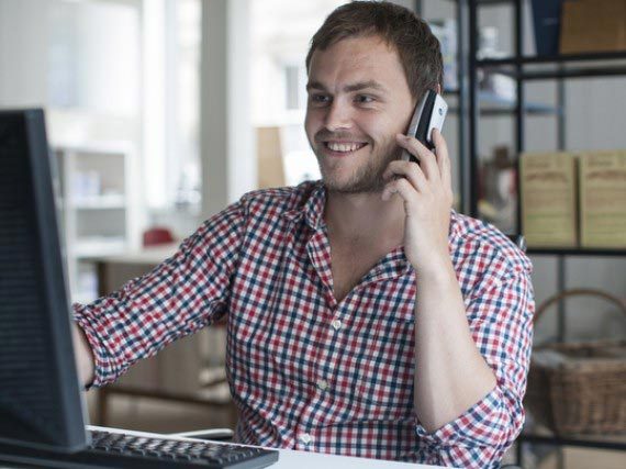 sales-executive-kieran-on-phone Young man in office smiling and talking on the phone